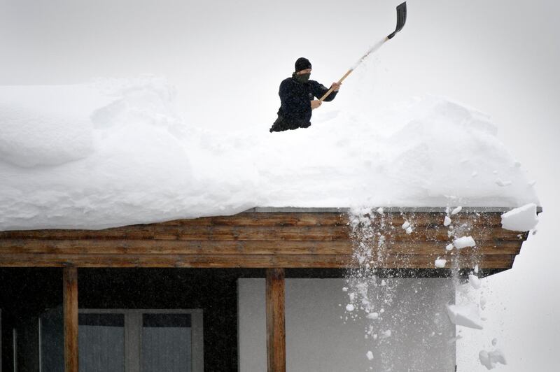 A Swiss police member removes fresh snow from the roof of the Kongress Hotel next to the Congress Centre on the eve of the 48th Annual Meeting of the World Economic Forum, WEF, in Davos. Laurent Gillieron