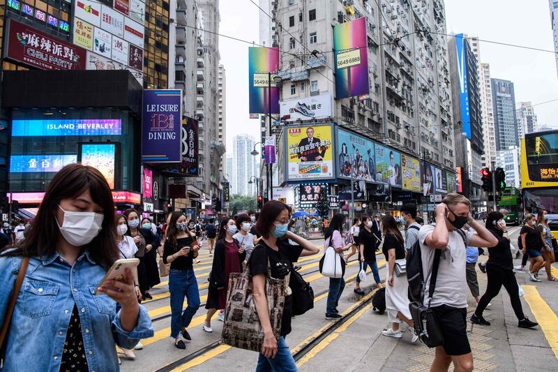 Pedestrians wear face masks as a precautionary measure against the COVID-19 coronavirus as they walk across a road in Hong Kong on May 13, 2020.  Two people in Hong Kong tested positive for coronavirus, officials said May 13, ending a 24-day run of no new local cases that saw the city begin to ease social distancing regulations. 
 / AFP / Anthony WALLACE
