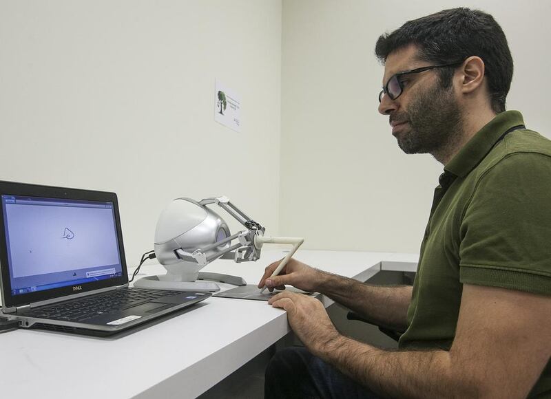 George Korres, a research engineer at New York University Abu Dhabi, demonstrates a haptic device that guides a person’s hand while they are writing in Arabic. Mona Al Marzooqi / The National