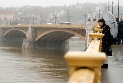 A woman standing and looks at Margit Bridge, where the wreck of a sightseeing boat was found on the Danube River, in Budapest, Hungary, Thursday, May 30, 2019. A massive search was underway on the river for over a dozen people missing after the sightseeing boat with 33 South Korean tourists sank after colliding with another vessel during an evening downpour. (AP Photo/Laszlo Balogh)