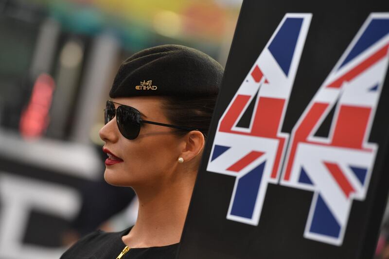 A member of the Etihad Airways cabin crew poses next to Lewis Hamilton's Mercedes. Andrej Isakovic / AFP