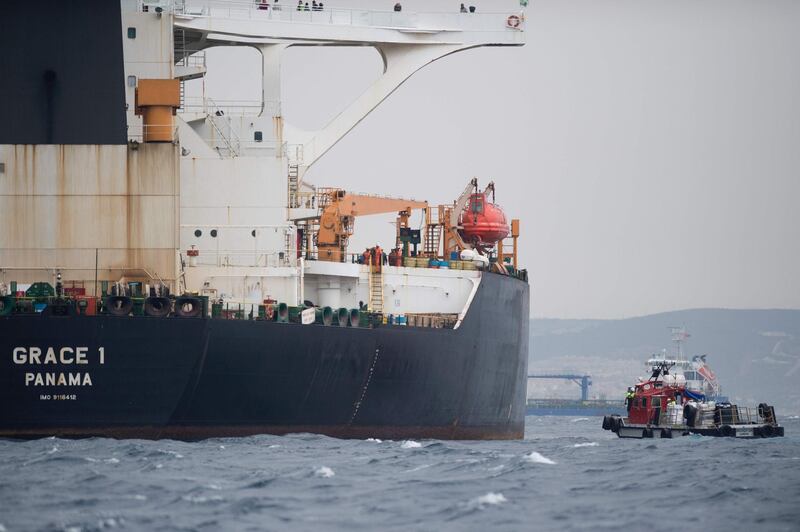 (FILES) In this file photo taken on July 06, 2019 A ship approaches supertanker Grace 1 off the coast of Gibraltar on July 6, 2019. Gibraltar police have arrested the Indian captain and chief officer of a seized Iranian tanker suspected of breaching EU sanctions by shipping oil to Syria, a spokesman for the Royal Gibraltar Police said on July 11, 2019. Iran demanded on July 5, 2019 that Britain immediately release an oil tanker it has detained in Gibraltar, accusing it of acting at the bidding of the United States. Authorities in Gibraltar, a British overseas territory on Spain's southern tip at the western entrance to the Mediterranean, said they suspected the tanker was carrying crude to Syria in violation of EU sanctions. / AFP / JORGE GUERRERO

