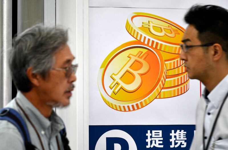 epa06360972 (FILE) - Pedestrians walk past a Bitcoin currency poster at the entrance of a Bic Camera electronics retailers store in central Tokyo, Japan, 01 June 2017 (reissued 01 December 2017). Finance experts have warned of a possible Bitcoin bubble after the cryptocurrency had reached an all-time high exchange rate on 29 November, following a massive gain over the past weeks.  EPA/FRANCK ROBICHON