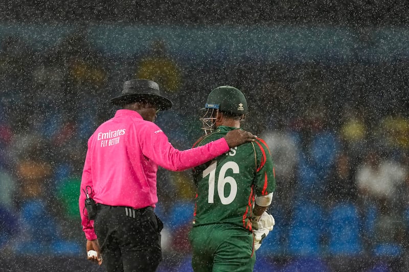 A match umpire talks with Bangladesh's Litton Das as rain stops play. AP