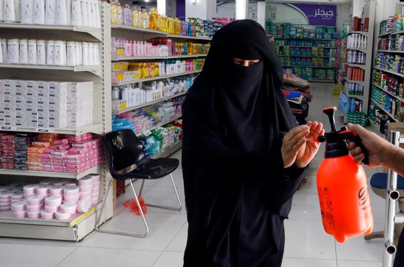 A worker disinfects the hands of a woman before she enters a supermarket in Sanaa, Yemen. EPA