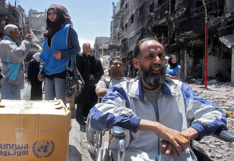 A photograph released by the official Syrian Arab News Agency shows people waiting for boxes of food aid being distributed by the United Nations Relief and Works Agency in the besieged Damascus suburb of Yarmouk on April 24, 2014. AFP