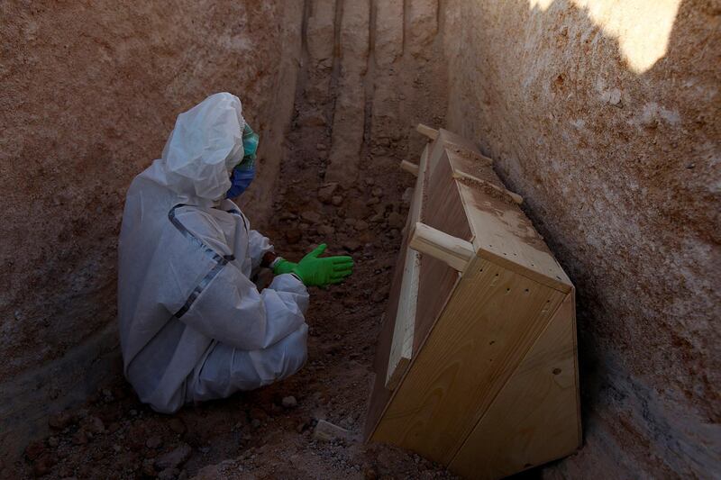 Abdelhussan Kadhim, from the PMF, who volunteered to work in the cemetery, wearing a protective suit, reads a verse from the Koran near the coffin of a man who passed away due to coronavirus, during his burial at the new Wadi Al Salam cemetery, which is dedicated to those who died of COVID-19, on the outskirts of the holy city of Najaf. REUTERS