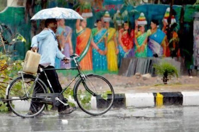 A cyclist and a pedestrian share an umbrella as they walk past a painted wall during showers in Hyderabad, India on Wednesday. The monsoon, crucial for India's agriculture, set over Kerala yesterday. Mahesh Kumar A / AP photo