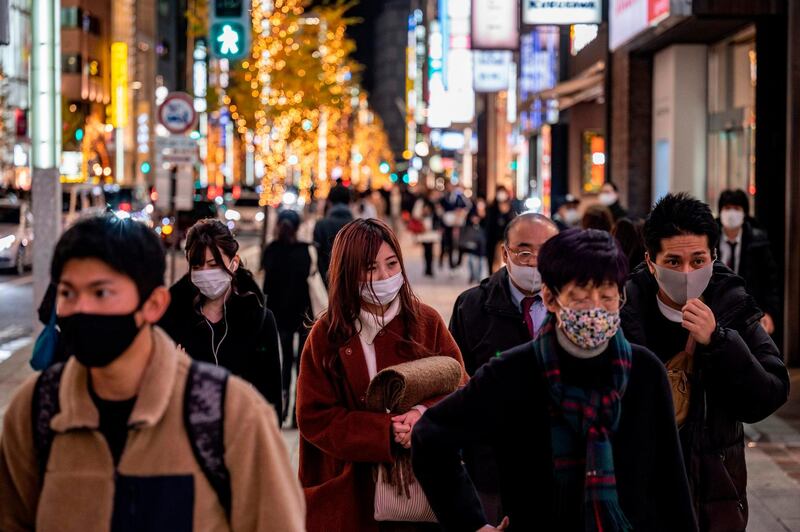 People walk on a shopping area on Christmas eve, in Ginza district of Tokyo on December 24, 2020. / AFP / Philip FONG
