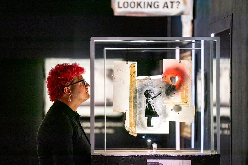 Gallery steward Louisa Mcgeachie stands next to the stencil piece of the Girl with the Heart Balloon. Getty