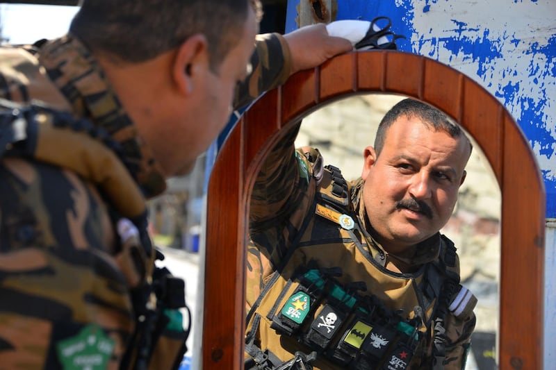 A member of the security forces checks his new haircut, provided by a volunteer hairdresser, in the northern Iraqi city of Mosul.  AFP