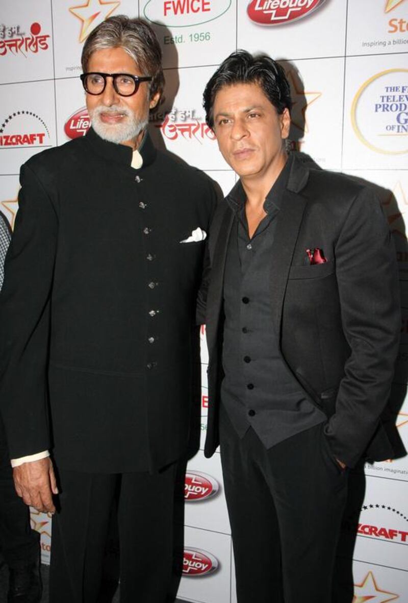 Indian Bollywood actor Amitabh Bachchan (L) and Shah Rukh Khan pose for the media as they attend a fundraiser event for the "Saath Hain Hum Uttarakhand" following the June flash floods in the northern Indian state that killed thousands, in Mumbai on August 15, 2013. AFP PHOTO/STR