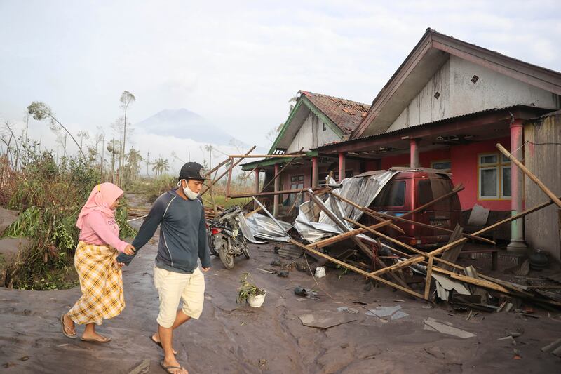 People walk near their damaged home. AP