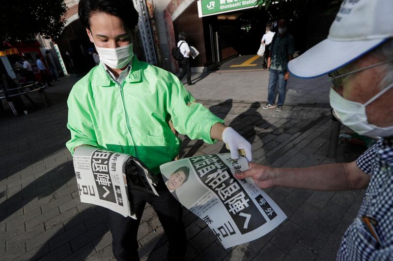 A man, right, receives an extra issue of Yomiuri newspaper in Tokyo on August 28, 2020, showing a report of Japanese Prime Minister Shinzo Abe's intention to resign due to his declining health. Hiro Komae / AP