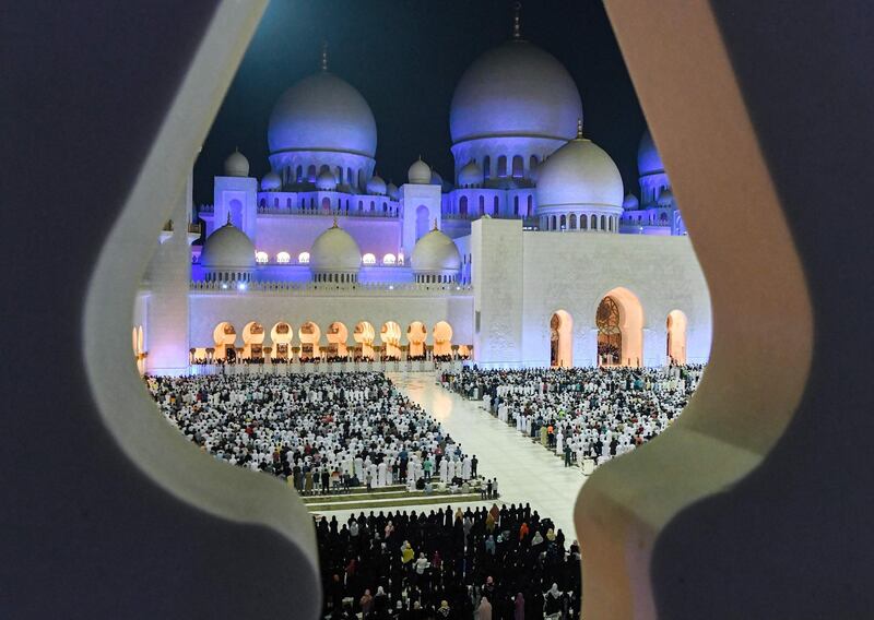 This picture taken early on June 1, 2019 through the crenellations of the Sheikh Zayed Grand Mosque in the UAE capital Abu Dhabi shows Muslim worshippers praying in the mosque's courtyard on the occasion of Lailat al-Qadr, which marks the night in the fasting month of Ramadan during which the Koran was first revealed to Prophet Mohammed in the seventh century.  / AFP / KARIM SAHIB
