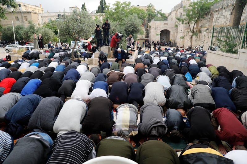 Journalists and TV crews film as Palestinian worshippers gather to attend the prayers of Eid al-Fitr, the Muslim holiday which starts at the conclusion of the holy fasting month of Ramadan, outside the closed Aqsa mosque complex in Jerusalem's old city early on May 24, 2020. - Muslims around the world began marking a sombre Eid al-Fitr, many under coronavirus lockdown, but lax restrictions offer respite to worshippers in some countries despite fears of skyrocketing infections. Jerusalem's Al-Aqsa mosque, Islam's third holiest site, will reopen to worshippers only after Eid, its governing body said. (Photo by AHMAD GHARABLI / AFP)