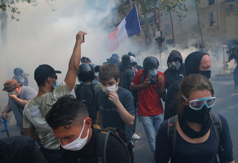 Yellow vest protesters escape tear gas fired by French police while wearing protective face masks as precaution against the conoravirus during a march in Paris, Saturday, Sept. 12, 2020. Activists relaunched France's yellow vest movement Saturday after the disruptive demonstrations against Emmanuel Macron's presidency and perceived elitism tapered off during the coronavirus pandemic.(AP Photo/Michel Euler)
