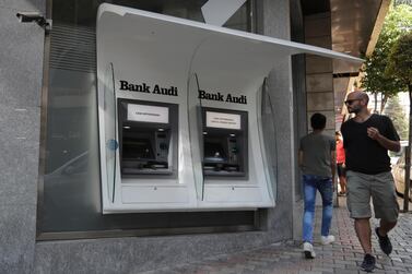 People pass by an out of service ATM machines at a closed bank in the Lebanese capital Beirut. AP
