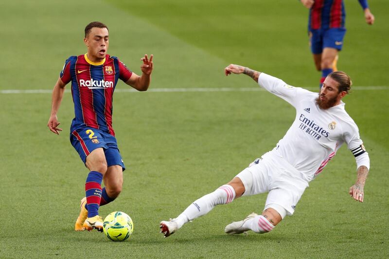 Real's Sergio Ramos launches a sliding tackle on Sergino Dest of Barca. Reuters