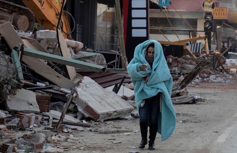 A woman walks past flattened buildings in a street in Hatay province, Turkey. Reuters