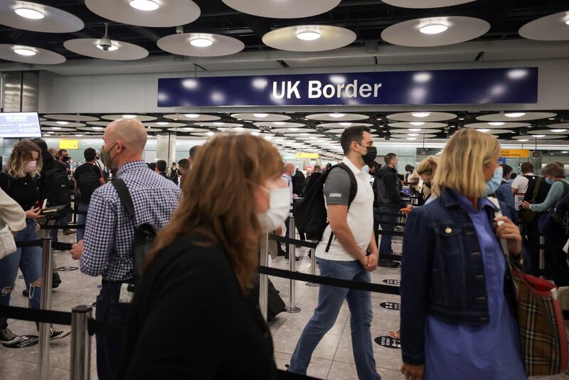 Passengers queue at Heathrow Airport. Under-18s travelling with fully vaccinated adults are also exempt from isolation when they return from an 'amber list' country.