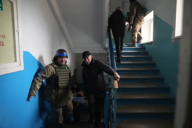 A Ukrainian serviceman and a civilian carry a wounded man who was injured by shelling in a hospital in Mariupol. AP Photo