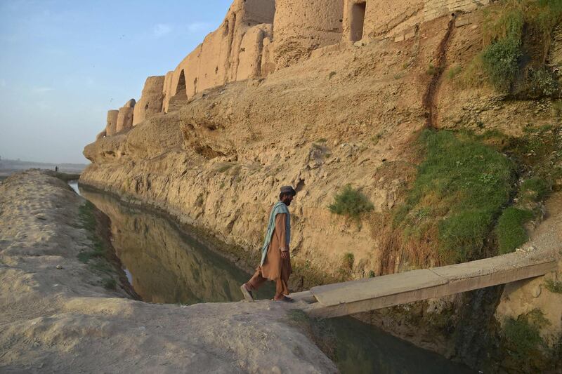 A man crosses a narrow bridge near the Qal-e-Kohna at Lashkar Gah river, in Helmand province on March 27, 2021.  / AFP / WAKIL KOHSAR
