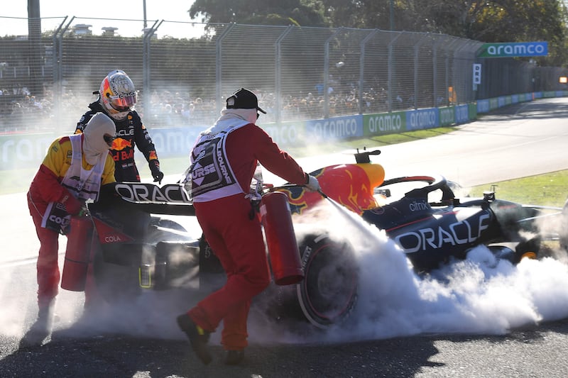 Marshalls try to extinguish fire as Max Verstappen looks at his car during the 2022 Formula One Australian Grand Prix. AFP
