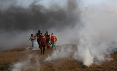 Medics evacuate a wounded youth in the middle of teargas fired by Israeli troops near the Gaza Strip border with Israel, during a protest east of Gaza City, Friday, Aug. 31, 2018. Gaza's Health Ministry says Israeli gunfire wounded about 80 Palestinians at a weekly protest along the border with Israel. (AP Photo/Adel Hana)