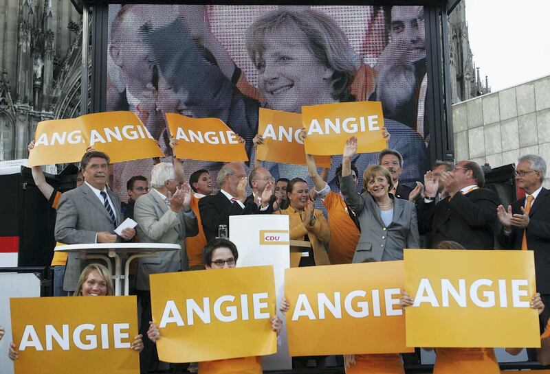 COLOGNE, GERMANY - AUGUST 10: Angela Merkel (R, waving), Leader of the Christian Democratic Party of Germany (CDU) speaks to supporters surrounded by banners at a campaign stop on August 6, 2005 in Cologne, Germany. Germany faces national elections on september 18, 2005. (Photo by Alexander Heimann/Getty Images)