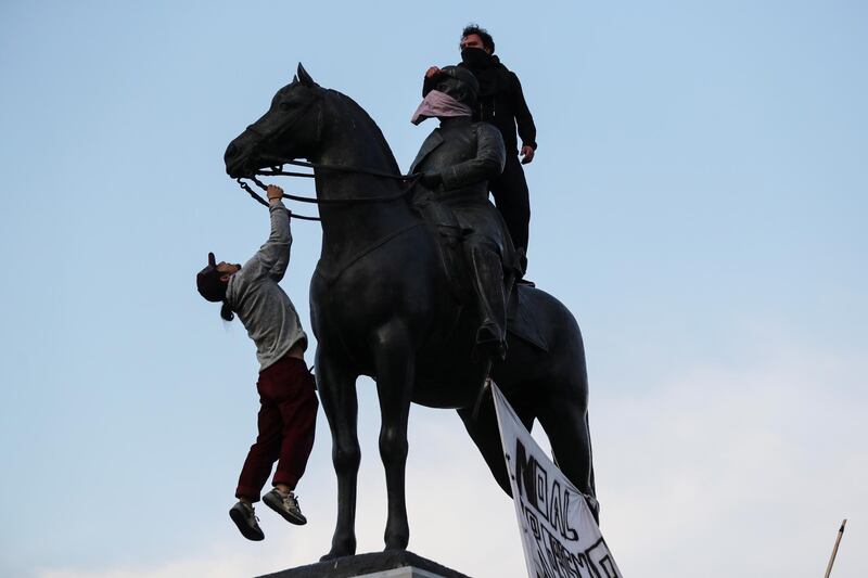 Demonstrators climb on top of the statue of general Manuel Baquedano during a protest against the increase in subway ticket prices in Santiago, Chile. Reuters