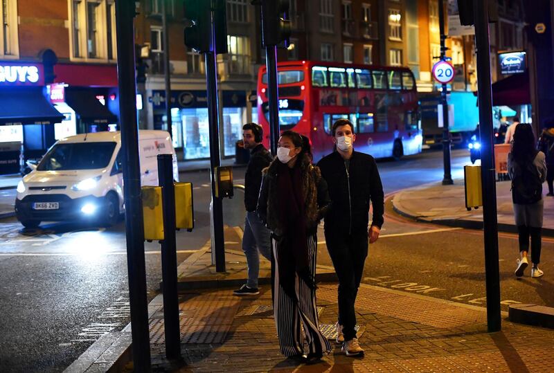 A couple wearing face masks walk down Clapham High Street in London, Britain March 16, 2020. Reuters