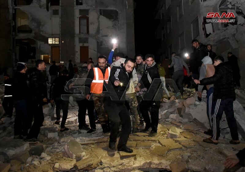 Rescuers carry a victim at the site of a collapsed building in Hama, Syria. AFP