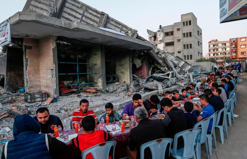 Palestinian families break their fast next to a destroyed building during recent confrontations between Hamas and Israel in the Gaza Strip. AFP