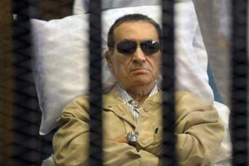 Egypt's ex-President Hosni Mubarak lies on a gurney inside a barred cage in the police academy courthouse in Cairo, during a hearing in which he was sentenced to life in prison.