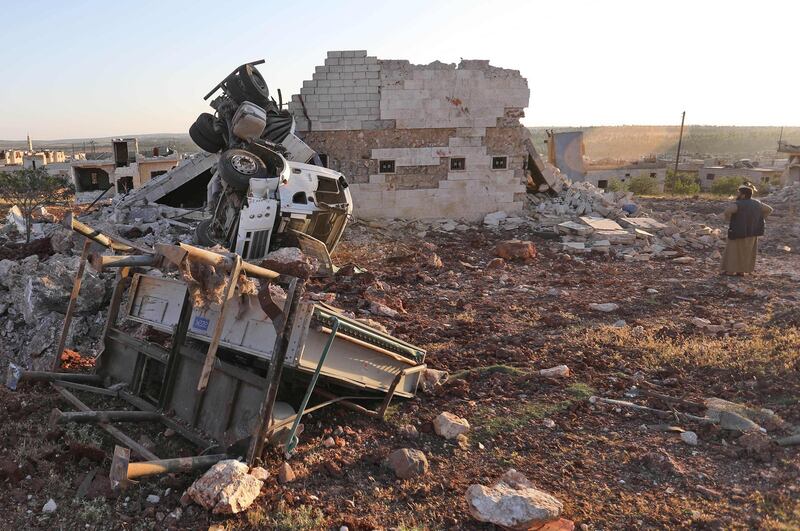 (FILES) In this file photo taken on May 20, 2019, a man gazes at rubble and damaged vehicles following reported air strikes by the Syrian regime ally Russia, in the town of Kafranbel in the rebel-held part of the Syrian Idlib province.  Syria's jihadist-controlled region of Idlib is home to some three million people, who have been variously affected by a surge in regime attacks since April. / AFP / OMAR HAJ KADOUR
