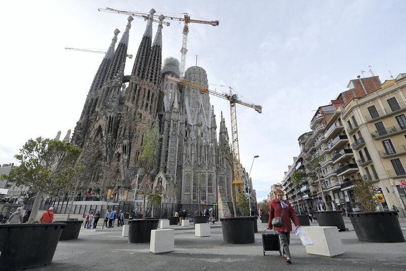 A woman pulls a shopping trolley  close to the Sagrada Famila (Holy Family) Basilica in Barcelona, on January 3, 2018. - The Sagrada Familia basilica, which was among the potential targets of the terrorist cell that committed attacks in Barcelona and Cambrils in August 2017, has reinforced security measures with new security gates and scanners. (Photo by LLUIS GENE / AFP)