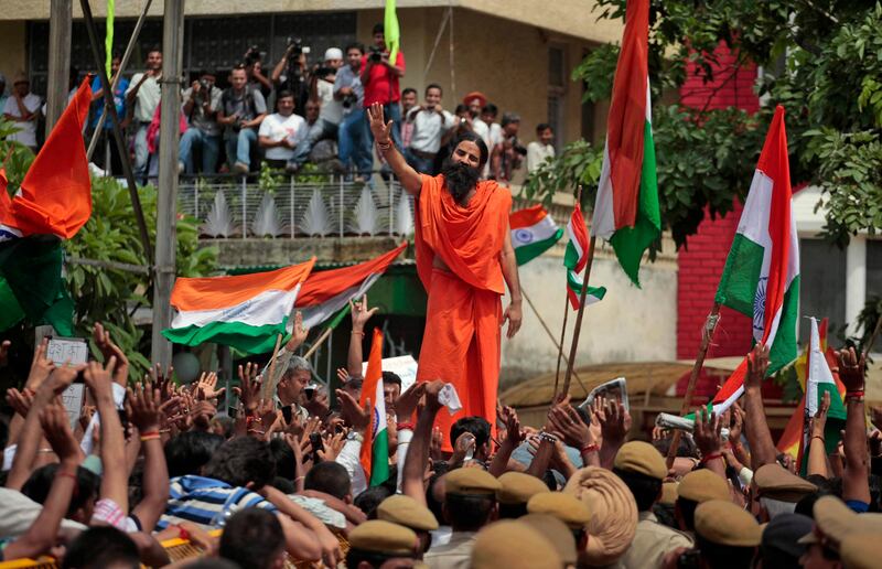 Indian yoga guru Baba Ramdev, center, waves to supporters of India's most prominent anti-corruption crusader Anna Hazare shout slogans as they gather in a show of support outside the Tihar prison complex where Hazare is holding his hunger strike in New Delhi, India, Wednesday, Aug.17, 2011. Police arrested Hazare on Tuesday to scuttle his plans to hold a public fast and tried to free him hours later. However, Hazare refused to leave the jail unless he was granted permission to hold a public demonstration aimed at forcing lawmakers to strengthen a draft bill that would create an anti-corruption ombudsman. Prime Minister Manmohan Singh lashed out at Hazare Wednesday, accusing the fasting activist of trying to circumvent democracy by demanding Parliament pass a reform bill he supports. (AP Photo/Saurabh Das) *** Local Caption ***  India Corruption Protest.JPEG-0ae69.jpg