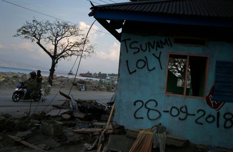 Motorists ride past a building damaged the tsunami in Loli Tasiburi village. AP Photo