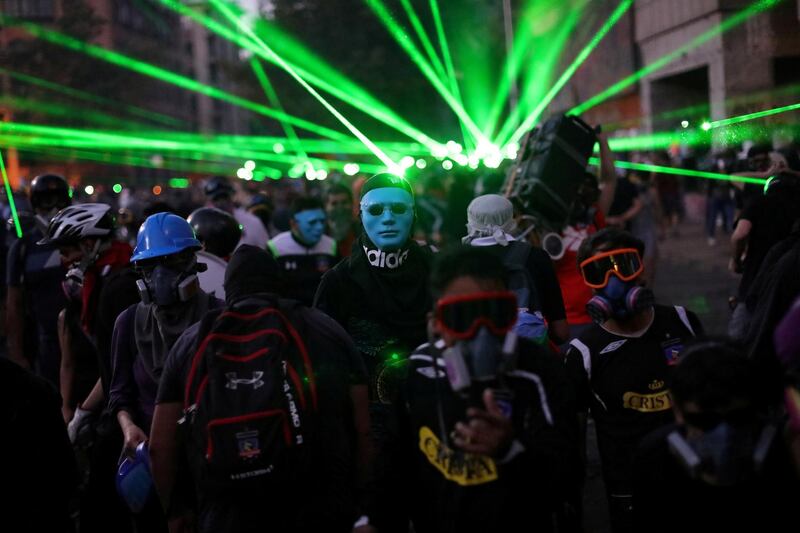 Laser beams are shone as masked demonstrators take part in a protest against Chile's government, at Providencia, a wealthy neighbourhood, in Santiago, Chile. Reuters