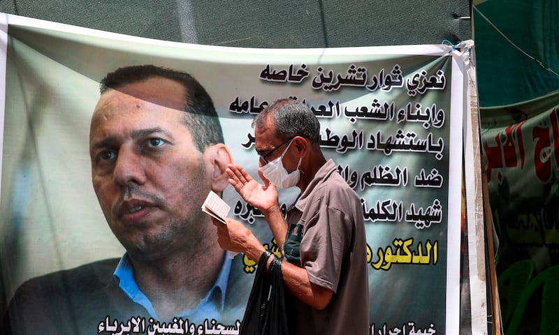 A protester prays by a banner featuring murdered analyst and academic Hisham Al Hashimi in 2020. AP