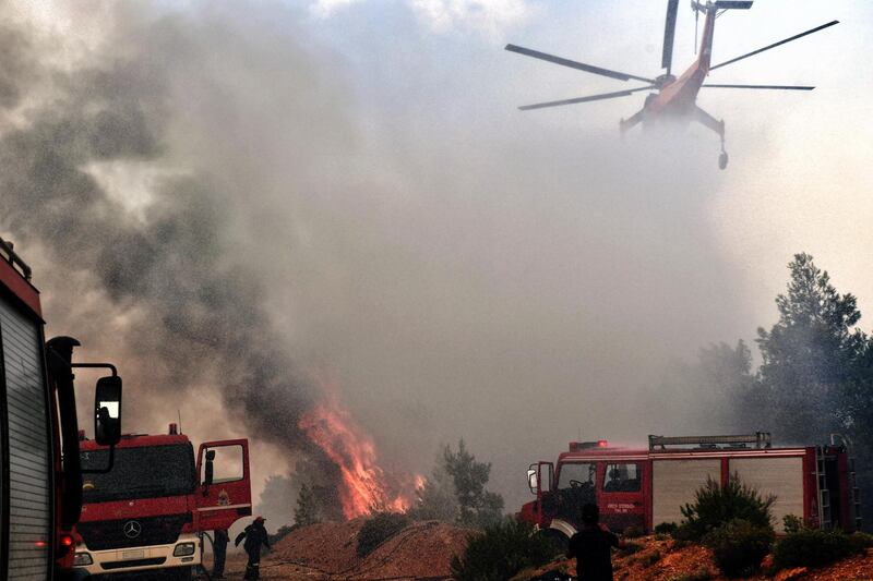 A firefighting helicopter and firemen try to extinguish a wildfire raging in Verori, near Loutraki city, Peloponnese. EPA