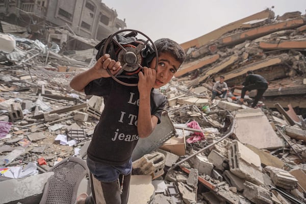 A boy carries a gas cooker amid the rubble in Nuseirat. AFP