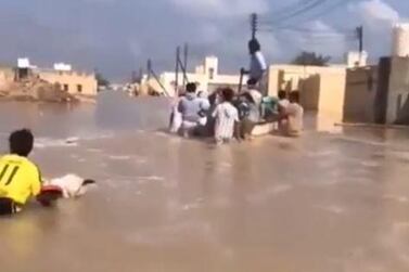 Residents wade through flood waters in in the coastal town of Ras Al Hadd, about 100km south of Muscat, on Tuesday morning