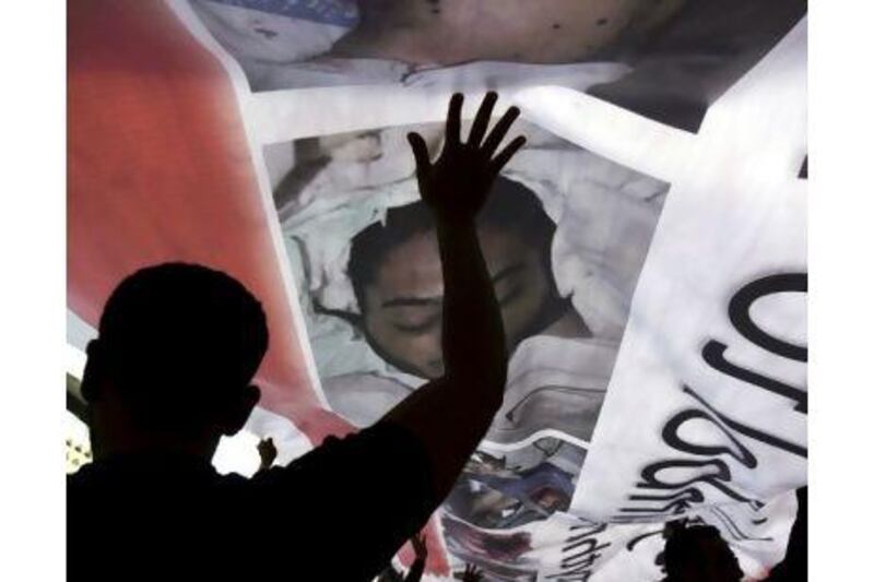 Protesters hold up a banner bearing photographs of those who have been killed in demonstrations in Manama.
