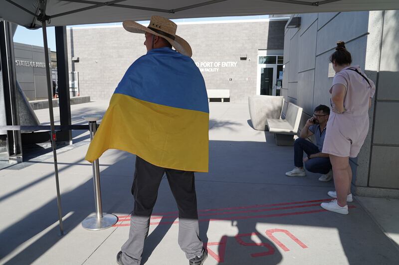 A man wearing a sombrero and draped in Ukrainian flag welcomes refugees on the US side of the border.