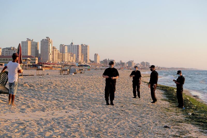 Palestinian police officers speak with a man as they patrol at a beach during a lockdown. Reuters