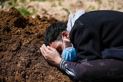 Umar Farooq mourns at the grave of his mother, who died of Covid-19 coronavirus, after her burial at a graveyard in Srinagar on April 26, 2021. / AFP / Tauseef MUSTAFA
