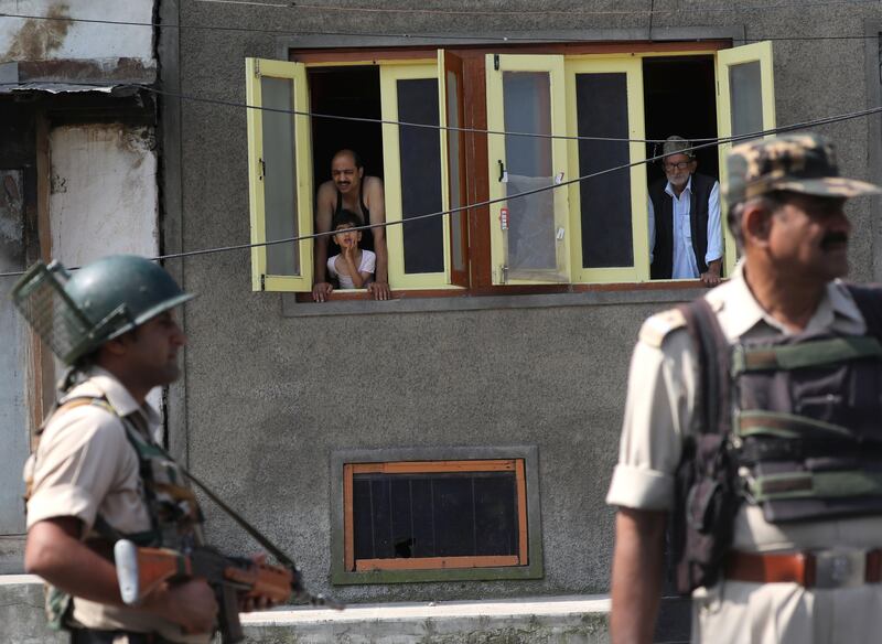 Kashmiris look from the windows of their home as Indian paramilitary soldiers stand guard near barbed wire during restrictions in the downtown area of Srinagar, the summer capital of Indian-controlled Kashmir, on July 8, 2017. Farooq Khan / EPA