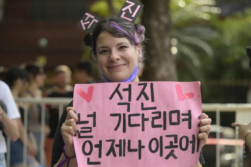 A fan holds up a sign in Korean for Jin ahead of the Coldplay concert.